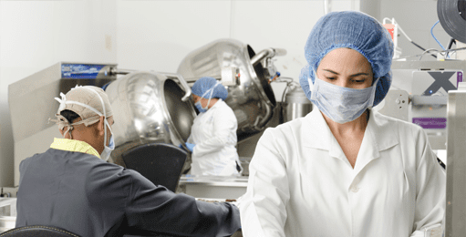 factory employees wear masks with industrial mixers in the background